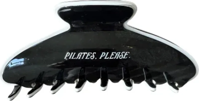 A black claw clip printed with the words Pilates, please.