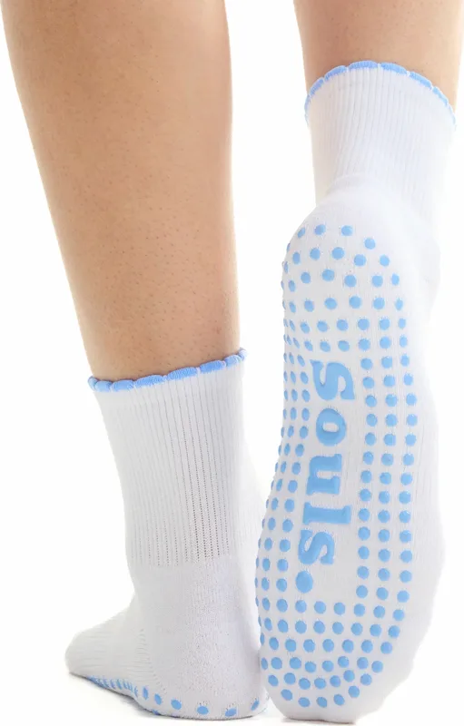 A pair of white grip socks with pale blue traction dots across the sole.